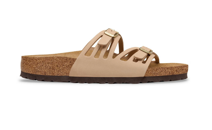 The Zertz GRANADA LENB SANDCASTLE R is a beige slide sandal in side profile, crafted from nubuck leather with two buckle straps, cut-out sides, a cork footbed, and a dark textured rubber sole for a natural look.