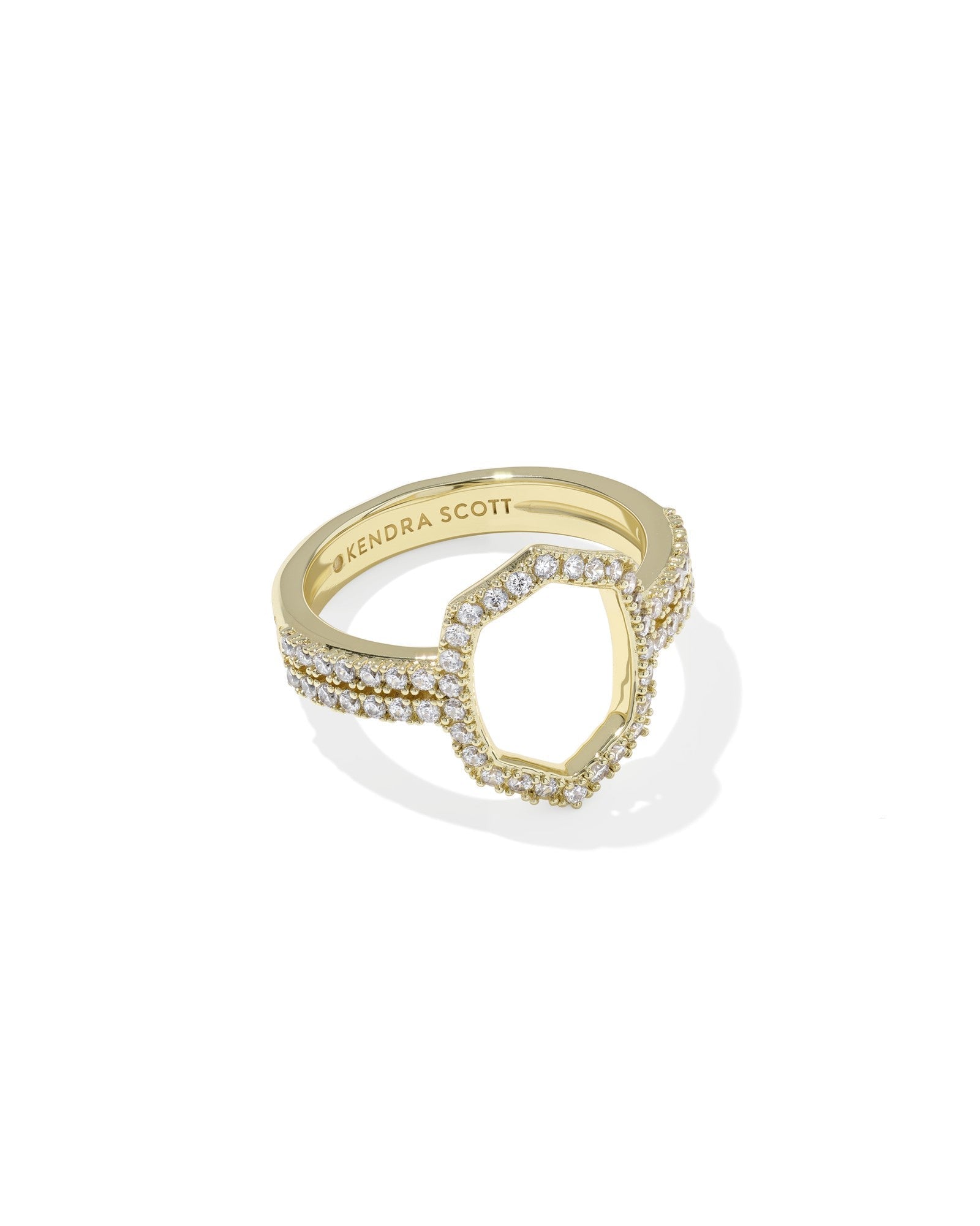 The Zertz DAPHNE PAVE COCKTAIL RING is a gold ring with pavé clear stones, a hexagonal open center, and “Zertz” engraved inside the band. Shown on a white background, it’s a stunning statement piece.