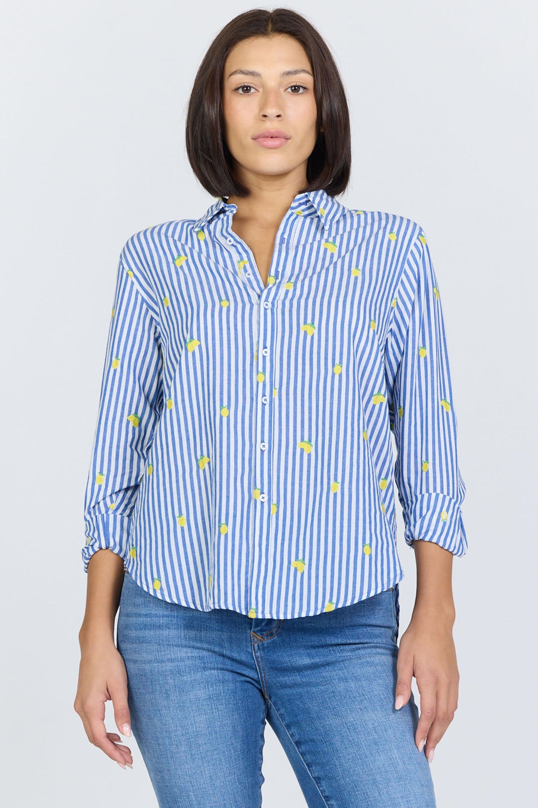 A person wearing the Zertz LOLITA TOP—a blue and white vertically striped button-up with yellow accents—and blue jeans stands facing forward against a plain light background.