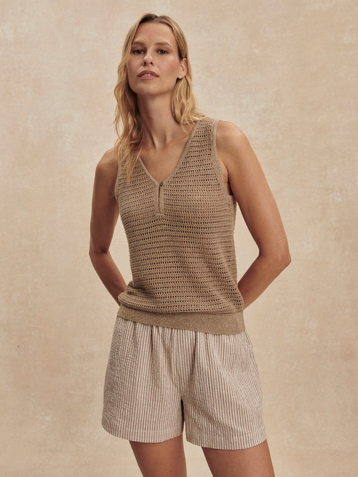 A woman stands against a neutral background in the Zertz RAMON KNIT TANK-SEPIA TWIST, a sleeveless V-neck top. Her relaxed confidence and blonde hair highlight this versatile layering piece’s fresh, effortless style with a subtle sepia hue.