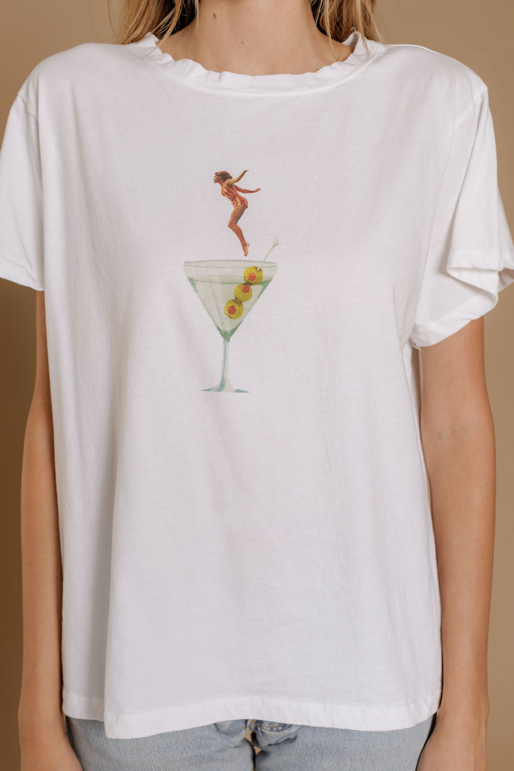 A woman models the Zertz DIP INTO MARTINI TEE, which showcases a playful graphic of a diver plunging into an olive-filled martini glass—a fun, casual choice for cocktail lovers.