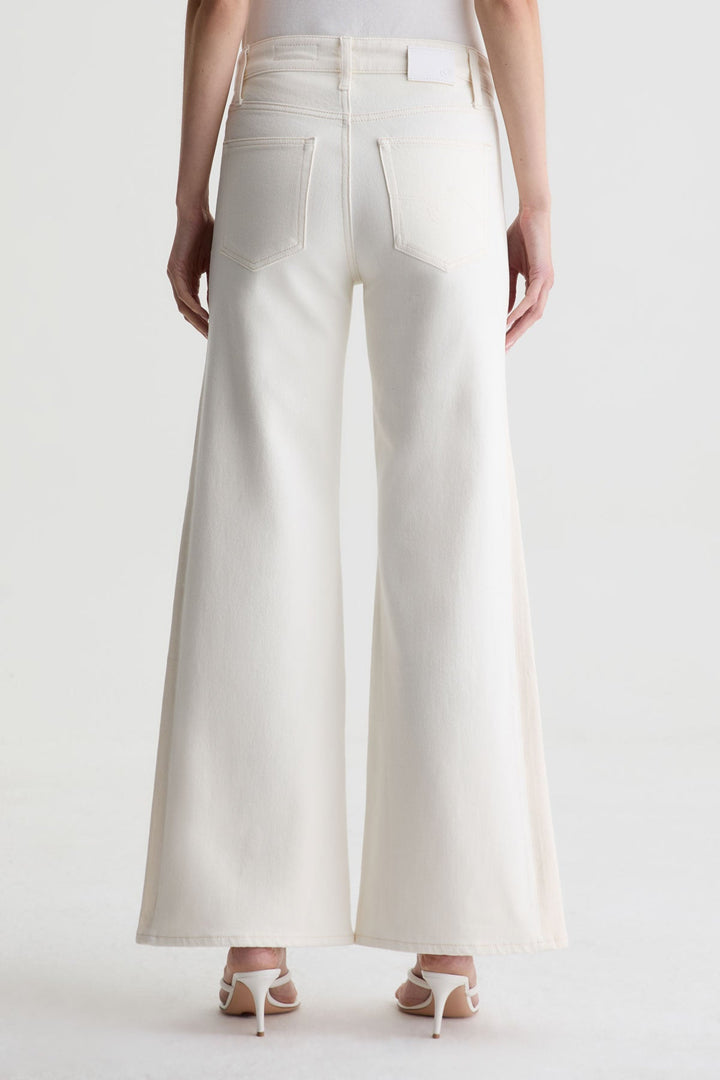 A person wearing Zertz’s SAIGE WIDE LEG MID RISE white jeans and white heeled sandals, shown from the back against a plain white background.
