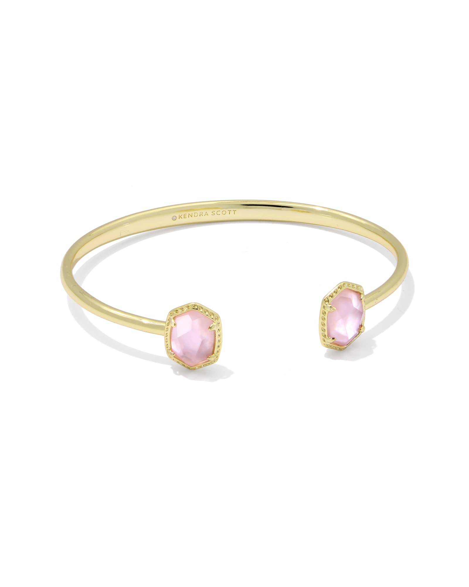 The DAPHNE FRAME CUFF BRACELET by Zertz features two light pink gemstones in hexagonal bezels on a gold cuff, with a structured design and an inner engraving.