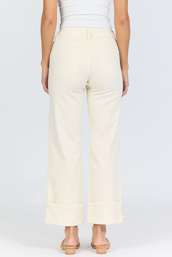 A person models the Zertz HOLLY JEAN high-waisted, wide-leg cream pants and a white sleeveless top, standing with their back to the camera against a light background, capturing timeless style.