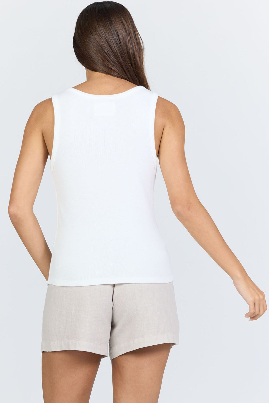 A person with long brown hair is shown from the back, wearing the Zertz LOUISE TANK in white and light beige shorts against a plain light gray background.