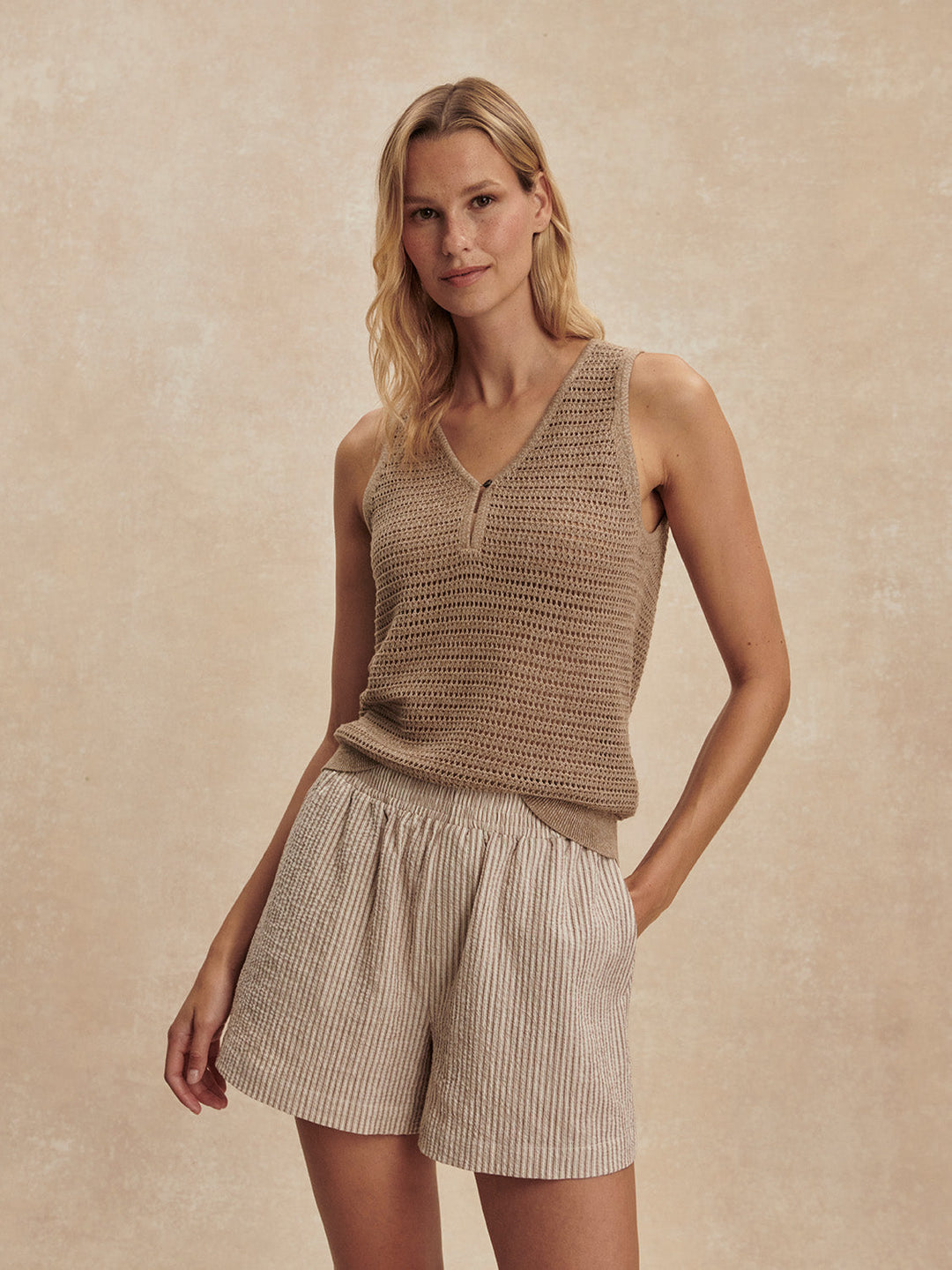 A woman models the Zertz DARINA SHORT 4 in Birch Taupe, pairing the relaxed fit shorts with a sleeveless knit top as she stands against a neutral backdrop, offering an effortless take on summer essentials.